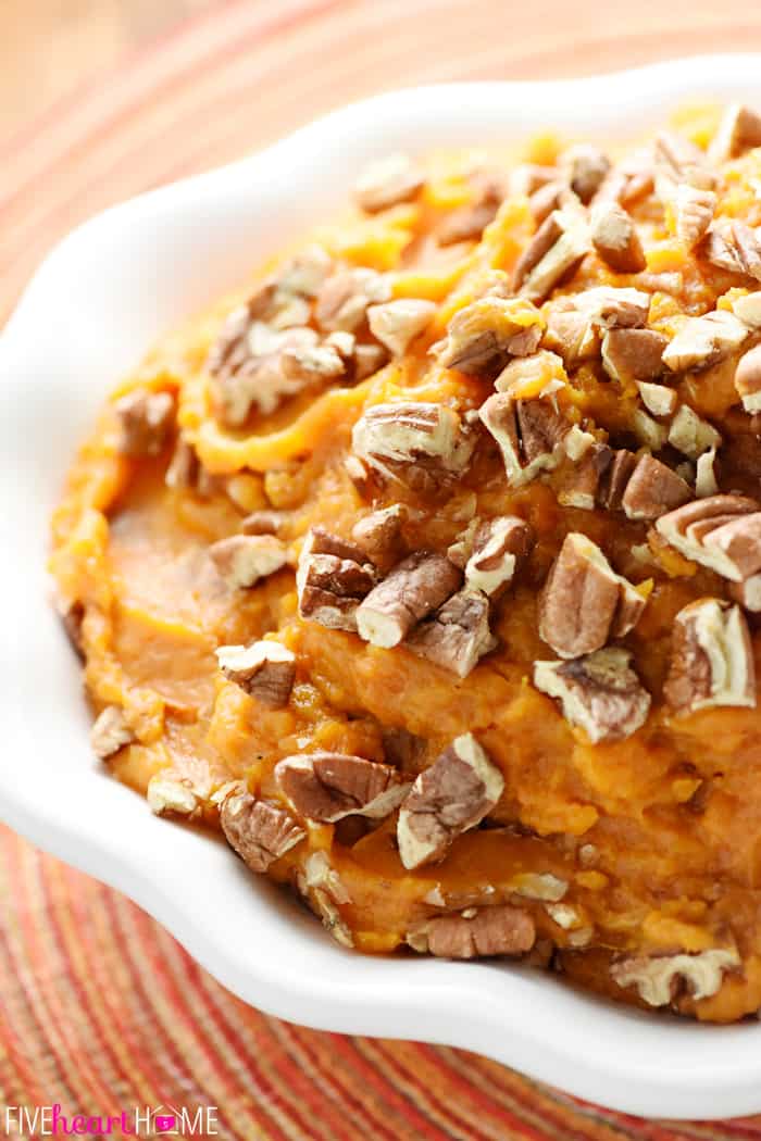 Crockpot Sweet Potatoes topped with pecans in serving dish.