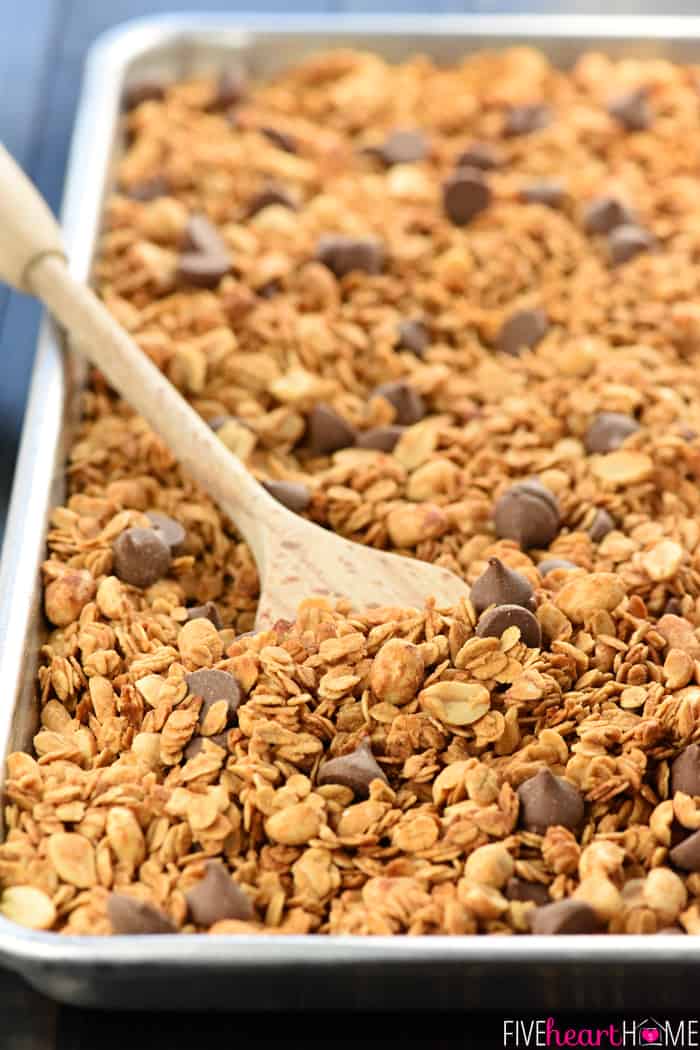 Baking sheet of Peanut Butter Granola recipe with wooden spoon.