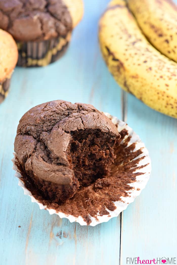 Solid chocolate muffin with liner peeled back and big bite missing