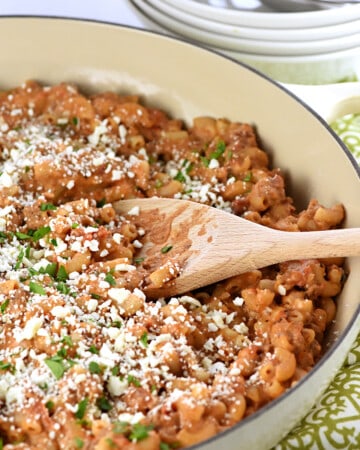 Pastitsio Recipe in a skillet with a wooden spoon.