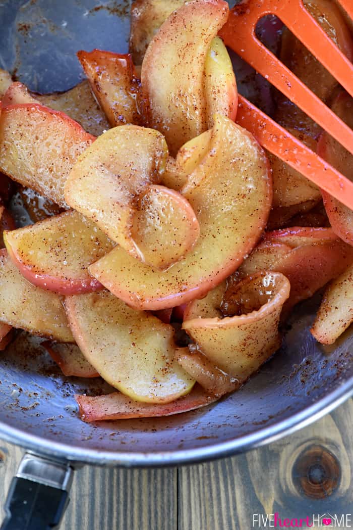 Cooked cinnamon apples in a pan being stirred by a spatula