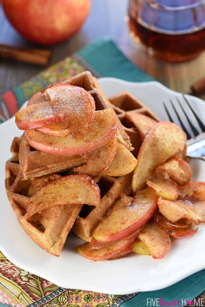 Whole Wheat Apple Cinnamon Waffles on a plate with a fork and maple syrup in the backgrounde