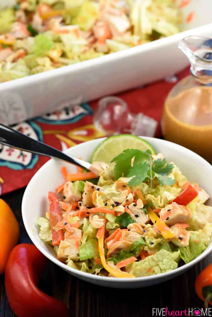 Thai Chicken Chopped Salad with Peanut Dressing ~ exploding with the contrasting flavors and textures of crunchy Napa cabbage, juicy chicken, colorful peppers, sweet carrots, salty peanuts, and fresh cilantro! | FiveHeartHome.com Served in a bowl with a wedge of lime and a sprig of cilantro