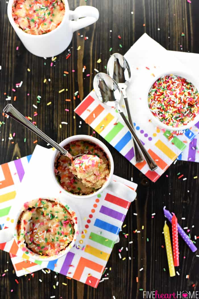 Aerial view of Funfetti Mug Cakes on napkins with sprinkles and candles scattered on table