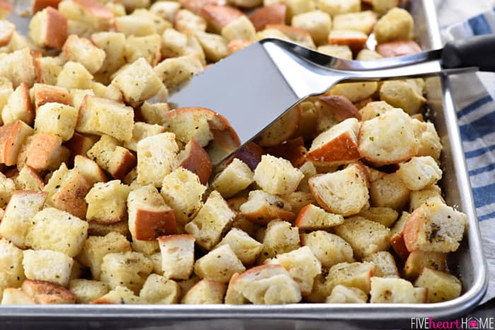 Crouton recipe on sheet pan with metal spatula.