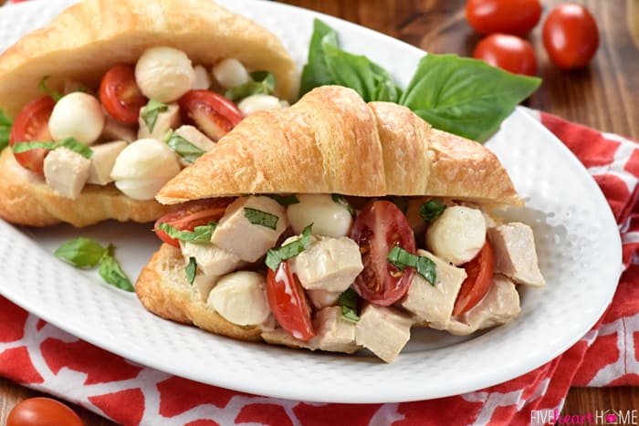 Caprese Chicken Salad on croissants on white platter.