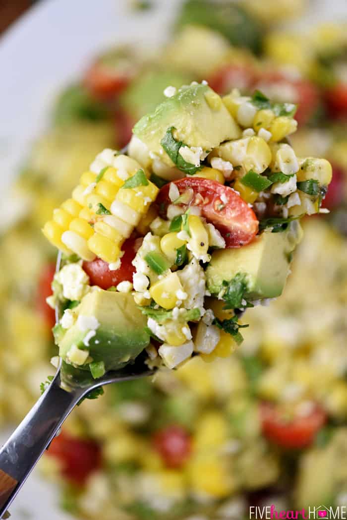 Corn Tomato Avocado Salad ~ an explosion of Tex-Mex flavors and summertime textures, with fresh roasted corn, juicy tomatoes, creamy avocado, minced jalapeño, crumbled cotija cheese, and fresh cilantro in a zippy lime vinaigrette! | FiveHeartHome.com Close-up of Corn Tomato Avocado Salad on serving spoon.