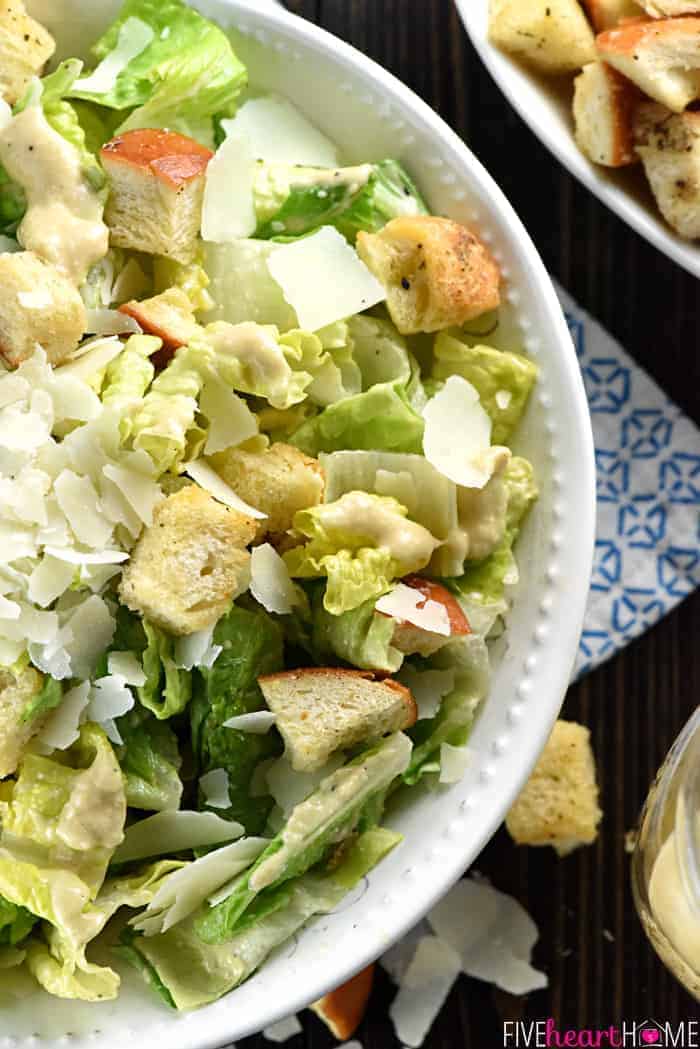 Aerial shot of serving bowl of romaine with shaved Parmesan and homemade croutons on top