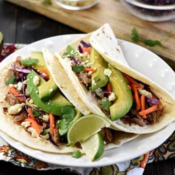 Slow Cooker Honey Lime Pulled Pork Tacos ~ tender, spicy-sweet pork piled on flour tortillas and topped with red cabbage, carrots, avocado, cotija cheese, and fresh cilantro for an easy, effortless dinner...and the leftover pork is fantastic on nachos! | FiveHeartHome.com