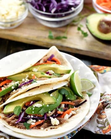 Slow Cooker Honey Lime Pulled Pork Tacos ~ tender, spicy-sweet pork piled on flour tortillas and topped with red cabbage, carrots, avocado, cotija cheese, and fresh cilantro for an easy, effortless dinner...and the leftover pork is fantastic on nachos! | FiveHeartHome.com