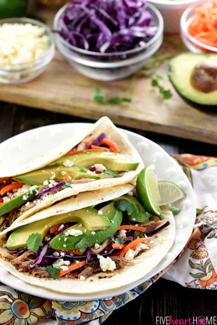 Slow Cooker Honey Lime Pulled Pork Tacos ~ tender, spicy-sweet pork piled on flour tortillas and topped with red cabbage, carrots, avocado, cotija cheese, and fresh cilantro for an easy, effortless dinner...and the leftover pork is fantastic on nachos! | FiveHeartHome.com