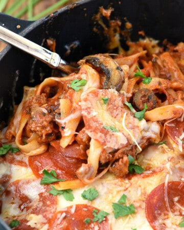 Spoon scooping Pizza Pasta out of black pot.
