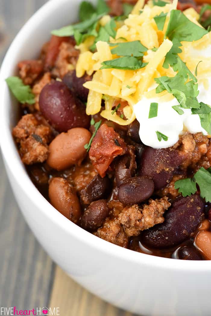 3-Bean Chili with beef close-up, topped with sour cream, cheese, and cilantro.