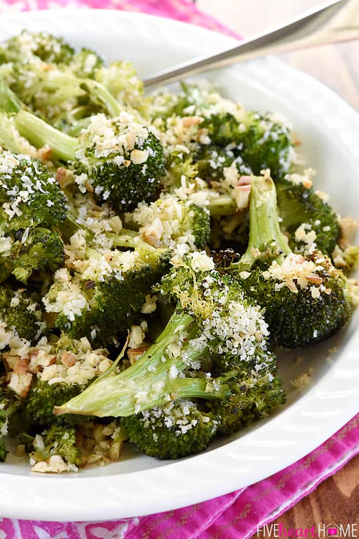 Close-up of serving dish of Parmesan Roasted Broccoli on pink cloth with spoon