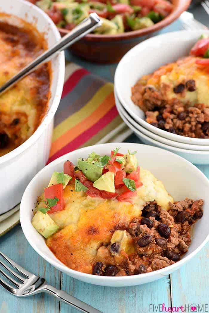 Taco Shepherd's Pie in a serving bowl topped with avocado tomato salad.
