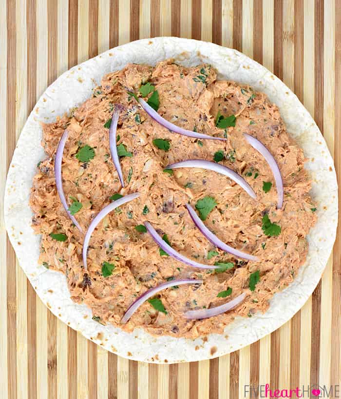 BBQ Chicken Tortilla Pinwheels ~ soft flour tortillas are slathered with a mixture of cream cheese, mozzarella, chicken, bacon, barbecue sauce, red onion, and cilantro, then rolled up tight and sliced in this flavorful, addictive appetizer recipe that's perfect for parties, potlucks, picnics, or game day! | FiveHeartHome.com Tortilla spread with filling and ready to roll up.