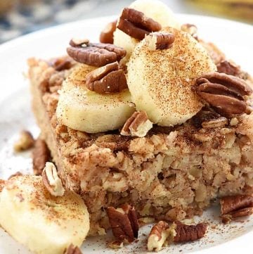 Banana Baked Oatmeal on a plate garnished with sliced bananas, toasted pecans, and cinnamon
