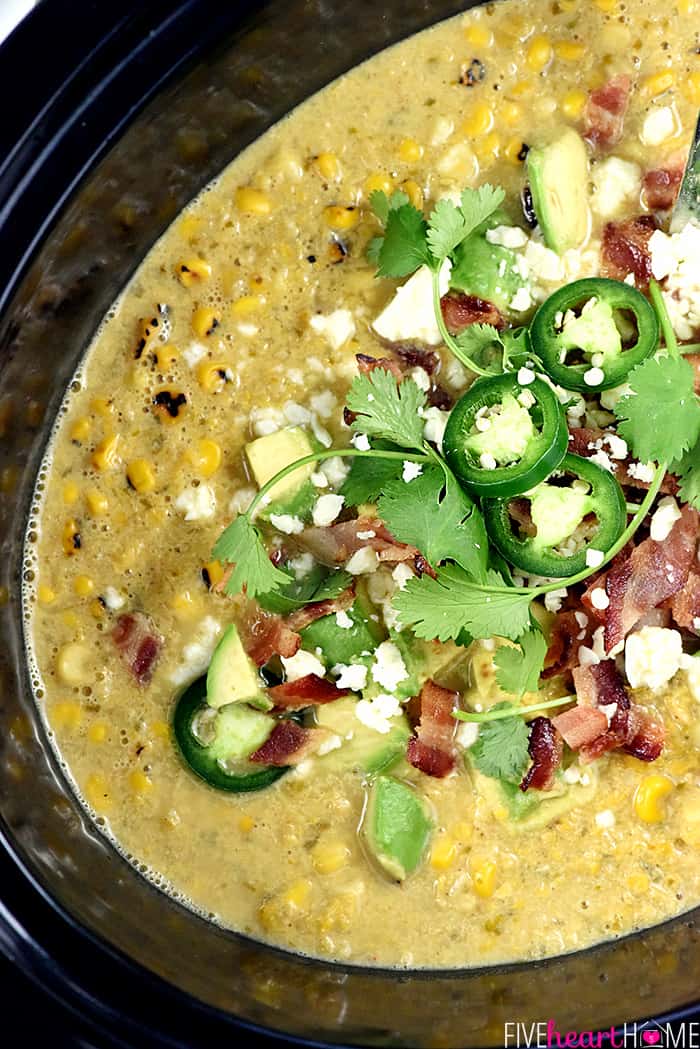 Slow Cooker Mexican Street Corn Chowder ~ the savory flavors of Mexican street corn come together in an easy crock pot soup that's slightly spicy, slightly smoky, and topped with avocado, bacon, cilantro, and cotija cheese! | FiveHeartHome.com Aerial view of Crockpot Corn Chowder with toppings.