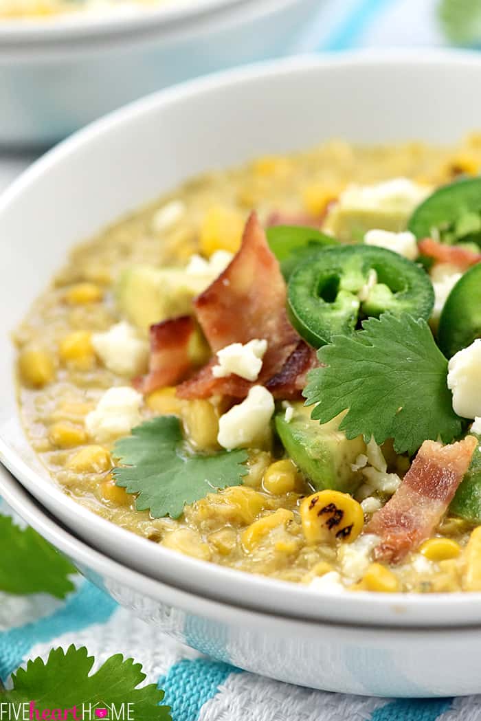 Slow Cooker Mexican Street Corn Chowder ~ the savory flavors of Mexican street corn come together in an easy crock pot soup that's slightly spicy, slightly smoky, and topped with avocado, bacon, cilantro, and cotija cheese! | FiveHeartHome.com Close-up in white bowl.