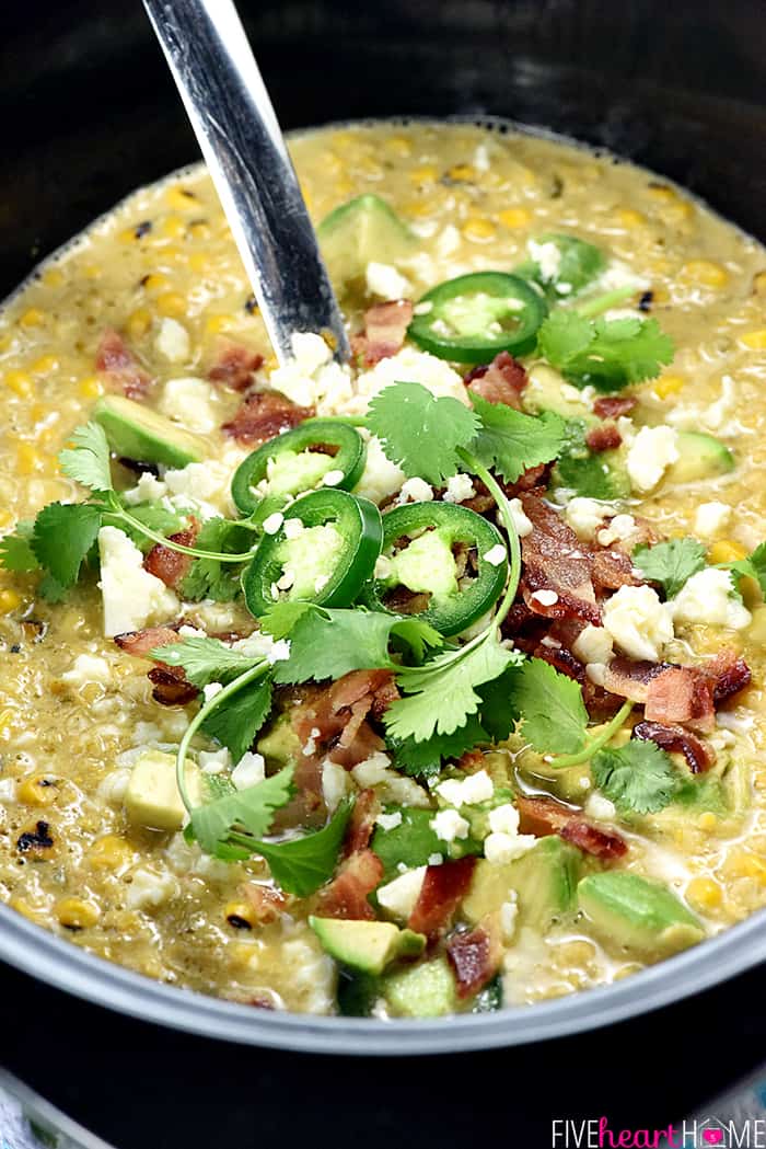 Slow Cooker Mexican Street Corn Chowder ~ the savory flavors of Mexican street corn come together in an easy crock pot soup that's slightly spicy, slightly smoky, and topped with avocado, bacon, cilantro, and cotija cheese! | FiveHeartHome.com Crockpot Corn Chowder in slow cooker with Mexican street corn garnishes.