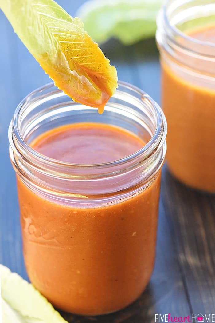 Lettuce leaf dipped into jar of homemade Catalina Dressing.