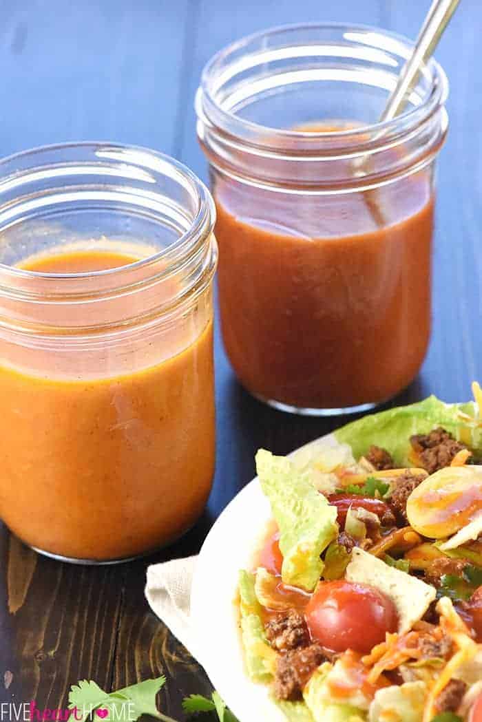 Two mason jars of French Dressing and Catalina Dressing, next to salad on a plate.