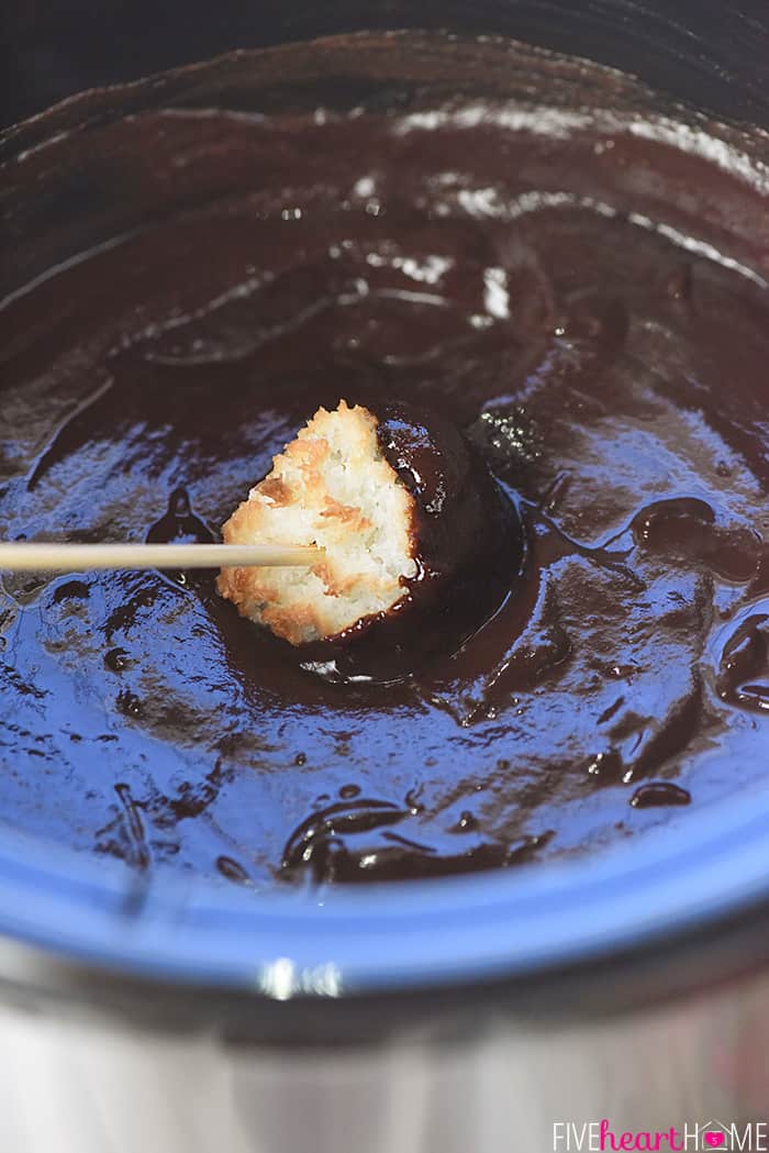 Coconut macaroon being dipped.