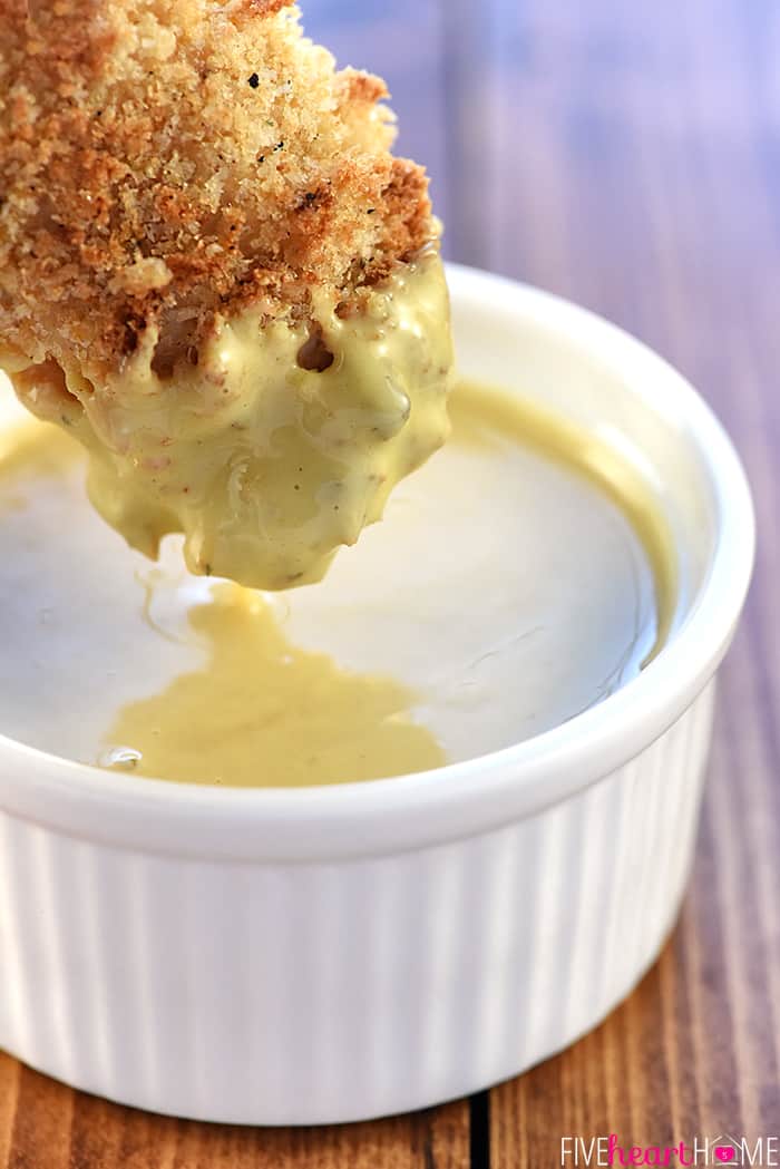 Chicken Tender being dipped in honey mustard sauce.