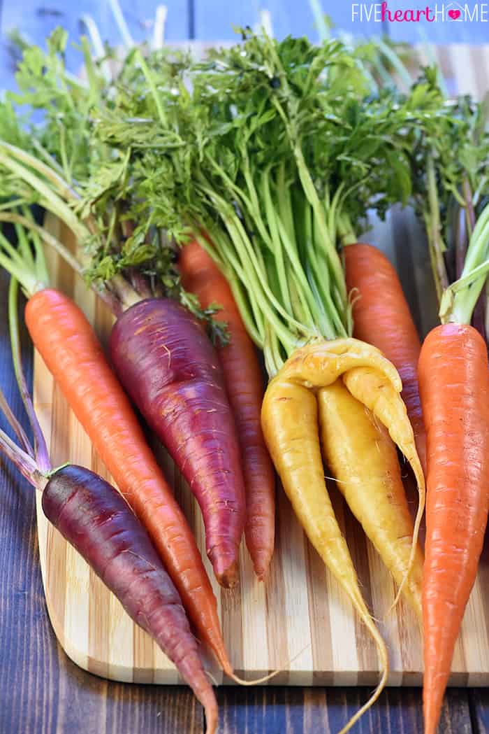 Raw rainbow carrots on cutting board.