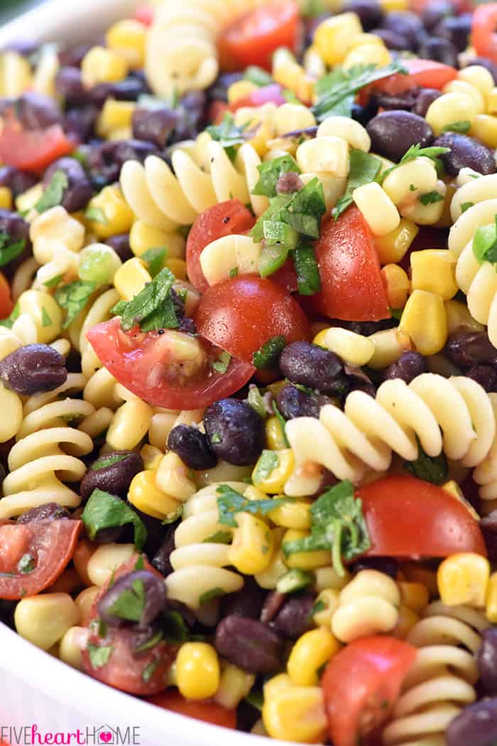 Close-up of ingredients in bowl, including corn, black beans, tomatoes, jalapeño, and cilantro.