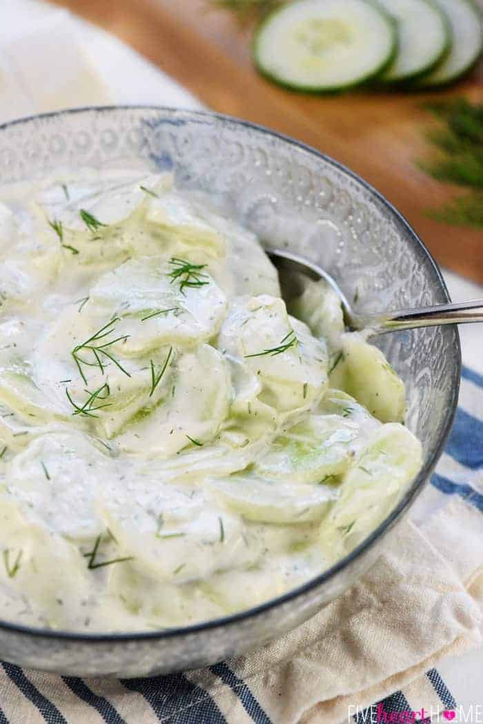 Creamy German Cucumber Salad, AKA Gurkensalat ~ a fresh and simple side dish featuring thinly sliced cucumbers in a sour cream and dill dressing! | FiveHeartHome.com Close-Up of Creamy German Cucumber Salad in Serving Bowl with Dill Garnish