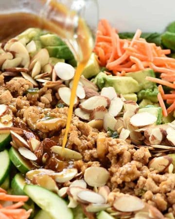 Dressing being poured over P.F. Chang's Chicken Lettuce Wraps Salad