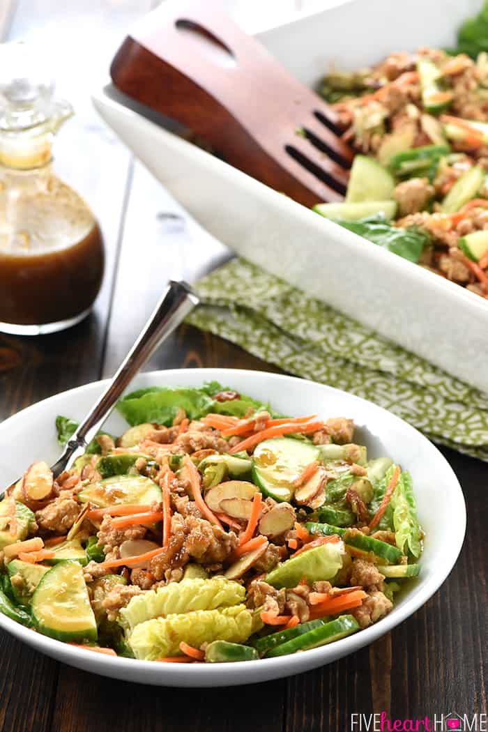 P.F. Chang's Chicken Lettuce Wraps Salad with serving dish in background, individual serving in foreground, and bottle of dressing to side