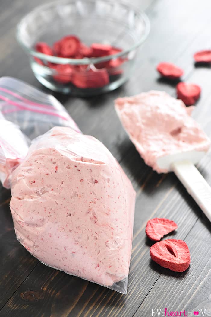 Piping bag ready to frost, with spatula and strawberries scattered on table