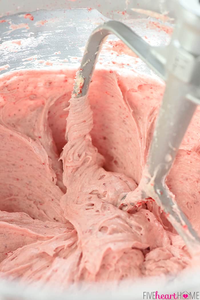 Close-up of frosting in electric stand mixer, being beaten by paddle