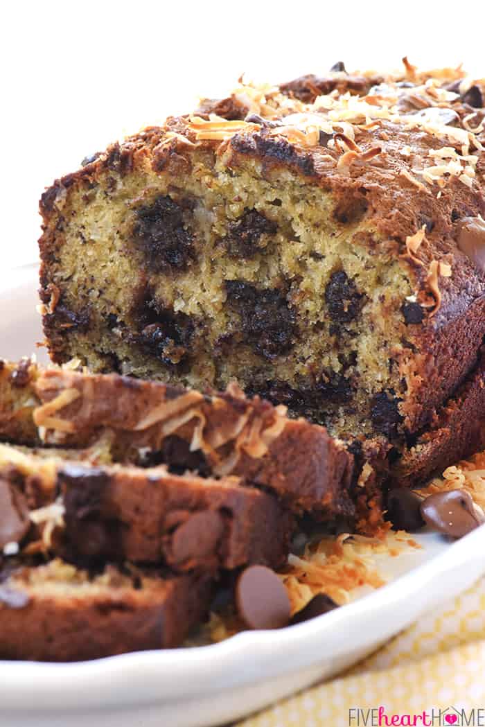 Loaf of Coconut Banana Bread with Chocolate, with a few slices cut, on platter