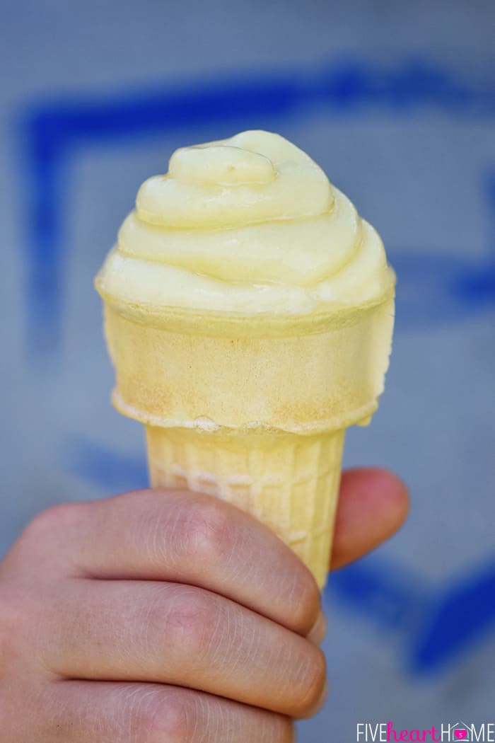Pineapple Whip in an ice cream cone held by a child's hand.