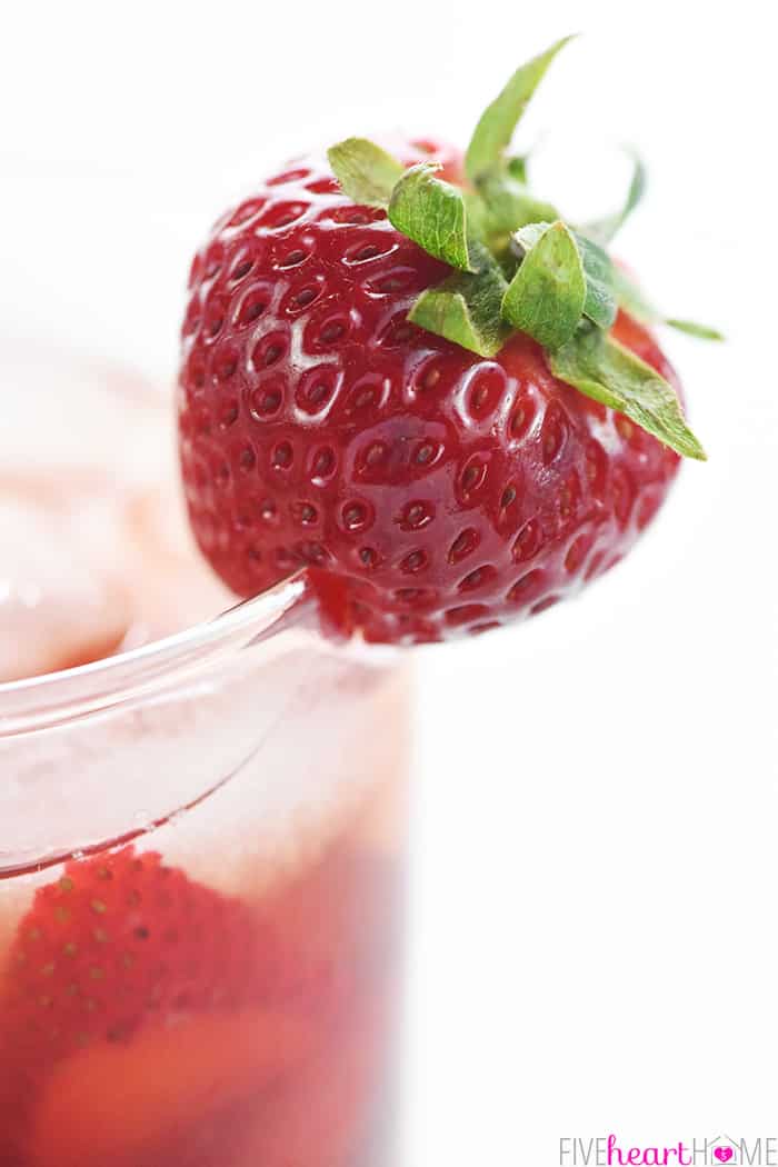 Whole strawberry garnish on rim of glass of tea