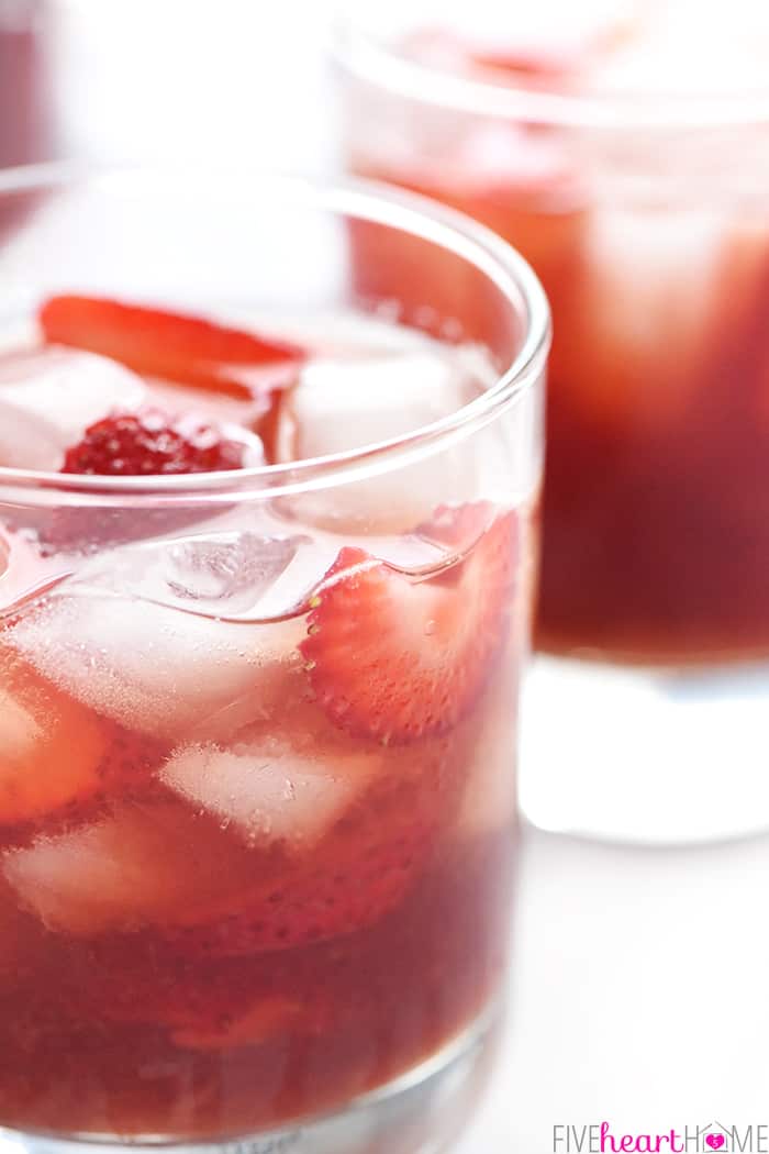 Strawberry Iced Tea ~ made with sweet, fresh, strawberry simple syrup for a refreshing summer drink! | FiveHeartHome.com Close-up of Strawberry Iced Tea in glass, with strawberry slices and ice floating in it