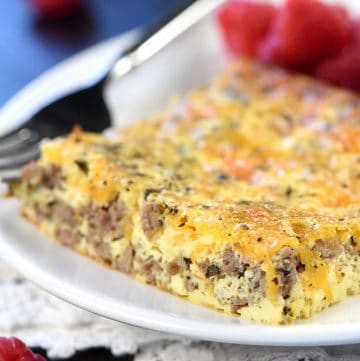 Slice of beef and cheese breakfast casserole on a plate with raspberries