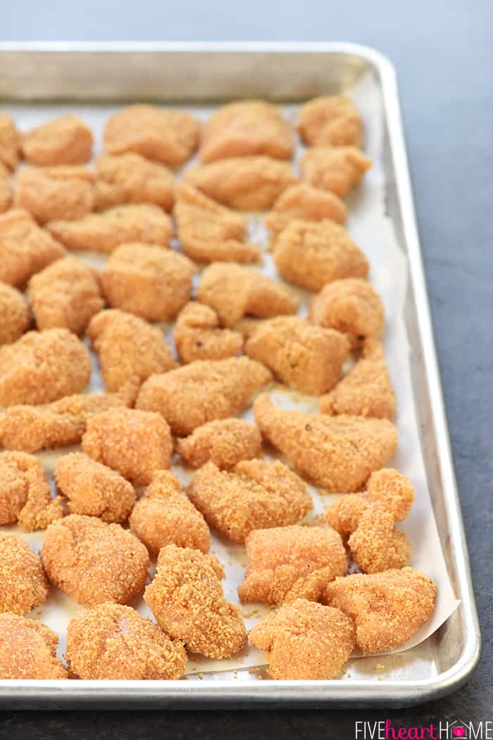 Homemade Chicken Nuggets ~ this recipe is made the QUICK AND EASY way, with a copycat "shake n bake" method yielding effortless, tasty nuggets that are a hit with kids and adults alike! | FiveHeartHome.com Homemade Chicken Nuggets on a baking sheet, ready for the oven.