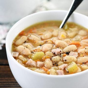 Crockpot Ham and Bean Soup in white bowl with spoon.