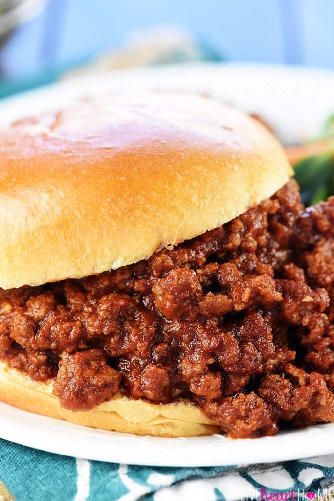 Easy Sloppy Joe Recipe close-up on bun, with sloppy joe sauce dripping onto plate.