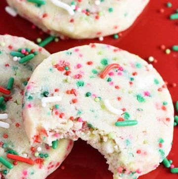 Christmas Shortbread Cookies on red plate with sprinkles.