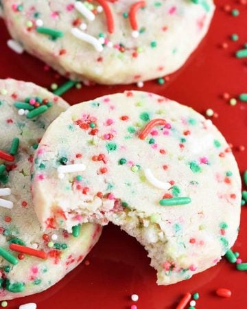 Christmas Shortbread Cookies on red plate with sprinkles.