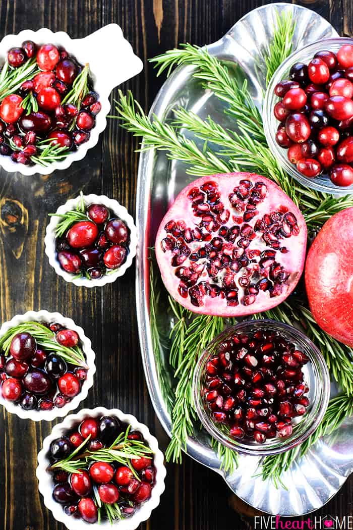 Easy Christmas Punch ~ a festive, sparkling, boozy holiday beverage featuring champagne, pomegranate juice, and cranberry juice that's perfect for Christmas or New Year's Eve parties...and it's easy to make a non-alcoholic version as well! | FiveHeartHome.com Aerial view of cranberries, pomegranates, and rosemary on platter.