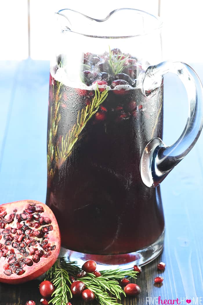 Easy Christmas Punch ~ a festive, sparkling, boozy holiday beverage featuring champagne, pomegranate juice, and cranberry juice that's perfect for Christmas or New Year's Eve parties...and it's easy to make a non-alcoholic version as well! | FiveHeartHome.com Glass pitcher of Christmas Punch recipe.