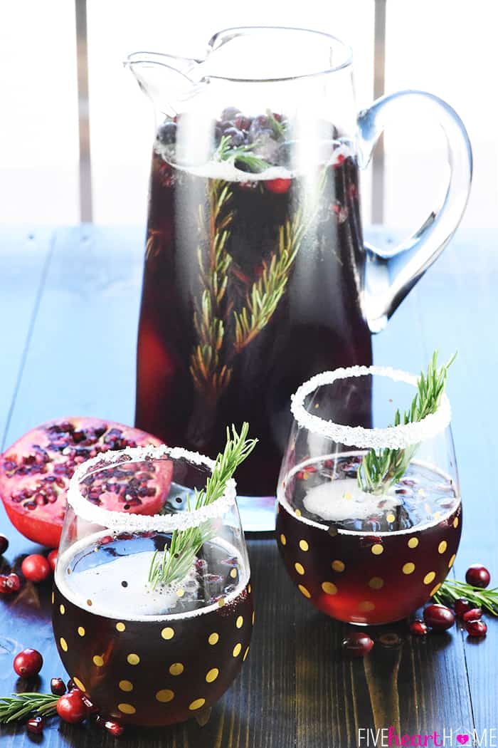 Easy Christmas Punch ~ a festive, sparkling, boozy holiday beverage featuring champagne, pomegranate juice, and cranberry juice that's perfect for Christmas or New Year's Eve parties...and it's easy to make a non-alcoholic version as well! | FiveHeartHome.com Christmas Punch in tall pitcher and two glasses.
