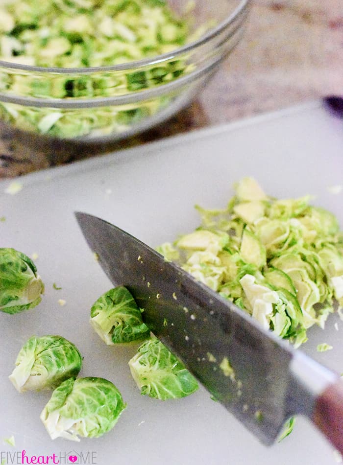 Knife shaving Brussels sprouts on cutting board.