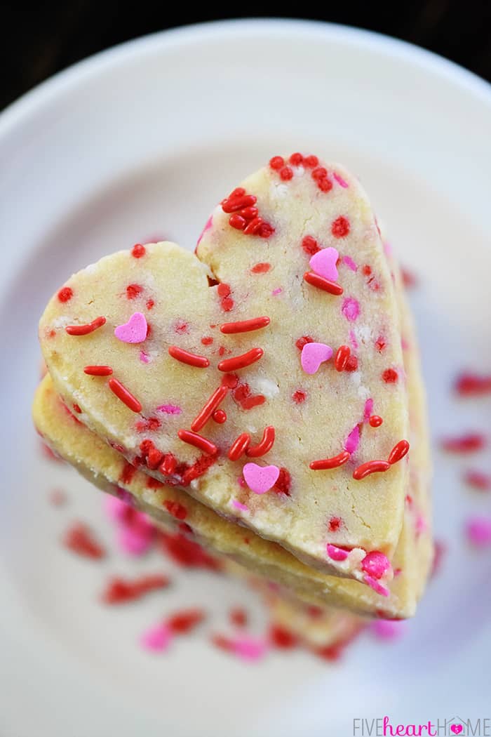 Aerial view of stack of heart shaped cookies with sprinkles.